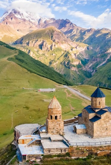 The Gergeti Trinity Church stands above the hills of Stepantsminda, overlooking the valleys of Kazbegi with Mount Kazbek rising in the background.