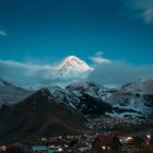 In Stepantsminda, Mount Kazbek and the charming Gergeti Church glow in the morning light, creating a captivating landscape among the mountains of the Caucasus.