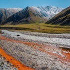 Mineral-rich stream in Truso Valley, where iron deposits color the ground creating one of the trek’s most distinctive landscapes.