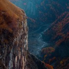 View over the mountains of Gudauri in autumn, where deep gorges, rocky cliffs and copper-colored forests shape dramatic landscapes in the heart of the Georgian Caucasus.
