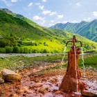 Mineral spring in Khada Gorge, where iron-rich waters emerge among alpine meadows and the green mountains of the Georgian Caucasus.
