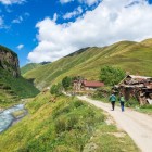 Trekking through Truso Gorge among ancient villages, mountain river and rolling green hills along the path in the Georgian Caucasus.