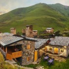 Stone guesthouse among the hills of Svaneti, with warm lights and medieval towers in the background. A simple, authentic place where evenings flow slowly in nature.