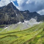 View of Mount Dolomisitsveri in the Greater Caucasus range, in the Racha-Lechkhumi region. Rocky ridges and green slopes shape the landscape.
