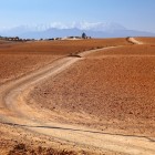 Dirt track in the Agafay Desert, among arid hills and wide open spaces with the Atlas Mountains in the background.