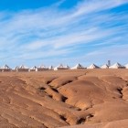 Tent camp in the Agafay Desert, among soft hills and arid landscapes, beneath the wide and bright sky of Morocco.