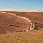 Dirt track in the Agafay Desert, among arid hills and wide open spaces with the Atlas Mountains in the background.