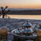 Mint tea served at sunset in the Agafay Desert, surrounded by silence, warm light and a pool overlooking the hills of Morocco.