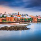 The historic walls of Rabat overlook the ocean among golden lights, calm waters and the elegant atmosphere of Morocco’s capital.