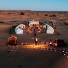 Luxury camp at sunset in Merzouga, among dunes, lanterns and elegant tents, to experience the authentic charm of the Moroccan Sahara.