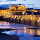 The Roman Bridge leads to Cordoba's magnificent Mosque-Cathedral, where lights, history and Andalusian charm are reflected on the Guadalquivir River in a breathtaking setting.