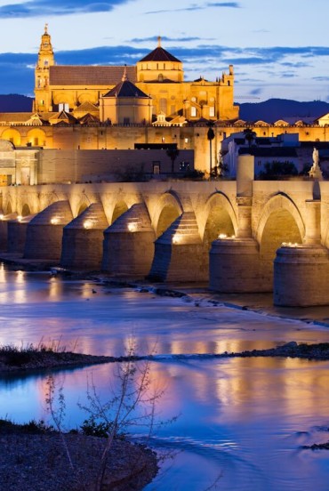 The Roman Bridge leads to Cordoba's magnificent Mosque-Cathedral, where lights, history and Andalusian charm are reflected on the Guadalquivir River in a breathtaking setting.
