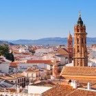 The tower of the Royal Collegiate Church of San Sebastián rises above Antequera's historic center, surrounded by white rooftops and timeless Andalusian scenery.