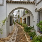 A charming archway leads into the narrow streets of Córdoba's Jewish Quarter, where whitewashed houses, cobblestones and Mediterranean plants reveal Andalusia's timeless beauty.