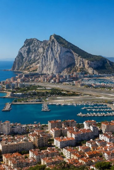 The Rock of Gibraltar rises above the coastline with its impressive limestone cliffs, overlooking the harbour and the Strait linking the Mediterranean to the Atlantic Ocean.