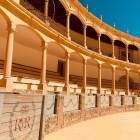 The elegant galleries of Ronda's Bullring feature stone columns and stacked arches, reflecting the city's historic Andalusian bullfighting tradition.