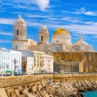 The Cathedral of Santa Cruz on the Sea dominates the skyline of Cadiz, overlooking the Atlantic amid historic walls, whitewashed buildings and the bright charm of the old town.