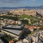 A breathtaking view over Athens showcases the New Acropolis Museum and the sacred hill crowned by the Parthenon, where ancient history meets the vibrant modern city.