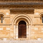 The Romanesque portal of the Church of San Martín de Tours welcomes pilgrims with timeless elegance, carved details and the golden stone of the 11th century
