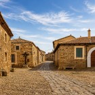 A quiet cobbled street winds through Castrillo de los Polvazares, lined with historic stone houses and authentic scenery that preserves the spirit of the Camino de Santiago.