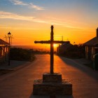 The Cruz de Ferro stands silhouetted against the sunset in Foncebadón, one of the Camino de Santiago's most iconic landmarks, where pilgrims leave a stone as a symbol of renewal.