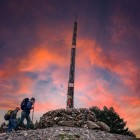 Two pilgrims reach the Cruz de Ferro at sunset, the most symbolic landmark of the Camino de Santiago, leaving a stone as a sign of hope and renewal.