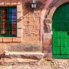Detail of a traditional stone house in Castrillo de los Polvazares, featuring its distinctive green doorway and architecture that reflects the village's muleteer heritage.