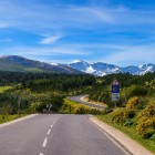 The road winds through the mountain landscapes of the Camino de Santiago, surrounded by forests, green hills and the peaks of the Sierra de Ancares on the way to O Cebreiro.