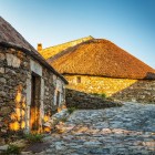 The ancient stone pallozas of O Cebreiro, bathed in the warm glow of sunset, preserve the village's Celtic heritage along the Camino de Santiago.