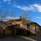Stone façade of a traditional inn in Foncebadón, a historic village on the Camino de Santiago, surrounded by mountain tranquillity beneath a clear sky streaked with delicate cirrus clouds.