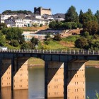 View of Portomarín with the bridge over the Miño River and the Fortress Church of Saint Nicholas overlooking the village, one of the Santiago Way's most iconic stops.
