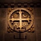 The ancient consecration crosses of Santiago Cathedral, with Alpha, Omega, the sun and the moon, commemorate the consecration of the basilica and symbolize Christ as the beginning and the end of all things.