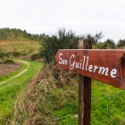 The sign pointing to San Guillermo guides pilgrims along the final trails of Finisterre, through coastal landscapes at Galicia's western edge.
