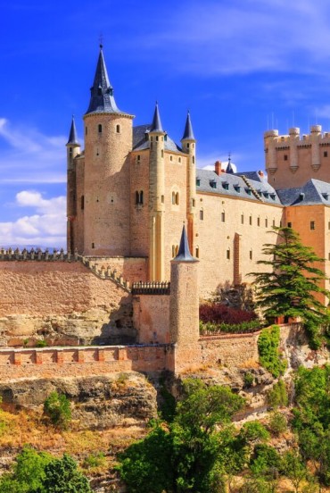 The medieval Alcázar of Segovia rises above a rocky hilltop. Towers, stone walls and slate roofs tell centuries of history in the heart of Castile.