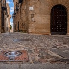 The cobblestones of Calle Amargura lead through Cáceres’ historic centre, past ancient stone façades and an arched doorway that preserves the city’s medieval atmosphere.