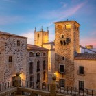 At sunset, Plaza de San Jorge reveals the historic heart of Cáceres, dominated by the tower of the Palace of Los Golfines de Abajo, within Extremadura’s UNESCO-listed old town.