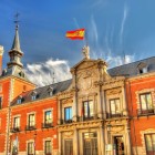 The façade of the Palacio de Santa Cruz reflects the formal style of Habsburg Madrid: red brick, granite, regular balconies and a carved portal crowned by the royal coat of arms.