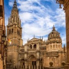 In the heart of Toledo, the Gothic façade of the Primate Cathedral rises amid historic buildings, distinguished by carved portals, pinnacles and its 15th-century tower.