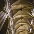The eye rises along Toledo Cathedral’s Gothic pillars towards the ribbed vaults, lit by stained-glass windows that emphasise the nave’s soaring vertical lines.