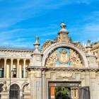 The Puerta de Felipe IV, built in 1690 by Melchor de Bueras for Mariana of Neuburg’s arrival, opens onto El Retiro’s Parterre with royal coats of arms and refined Baroque ornaments.