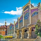 Architecture and colour define Mercado de Colón: brick arches, mosaics and stained glass express Valencian modernism in a historic space dedicated to food and social life.