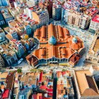 Seen from above, Mercado de Colón rises in the heart of Valencia’s Eixample: its modernist brick structure blends into the dense urban grid and colourful rooftops