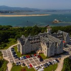 Aerial view of La Magdalena Palace, a former royal residence with eclectic architecture, surrounded by gardens and pine trees overlooking Santander Bay and the Cantabrian Sea.
