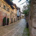 Calle del Cantón’s cobblestones trace centuries of history past Casa de los Hombrones, with its arched portico and Baroque crest, and ancient stone houses.