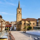 Plaza de la Constitución, in the heart of Comillas, invites you to stroll among Cantabrian houses and terraces beneath San Cristóbal’s historic stone tower.