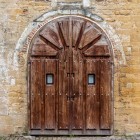 The portal of San Miguel de Lillo preserves an intimate, austere entrance: the stone arch and massive wooden door lead into the silence of the Naranco sanctuary.