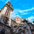 In Plaza Fernando Rubio, the Basilica of San Juan el Real, designed by Luis Bellido and opened in 1915, blends Neo-Romanesque and Byzantine forms through its towers and red dome.