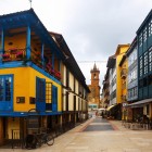 Calle Fierro crosses the heart of El Fontán amid colourful façades, flower-filled balconies and glazed galleries, leading the eye towards San Isidoro el Real’s Baroque tower.