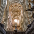 In Astorga Cathedral’s choir, carved wooden stalls and the monumental organ lead the eye towards the star-shaped vaults, where ribs and gilded bosses enhance the Gothic verticality.