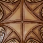 Looking upward inside Astorga’s Episcopal Palace, brick ribs form a geometric cross among perforated motifs: a detail where Gaudí blends technique and imagination.